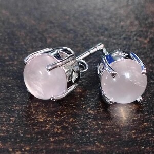 Könnte beinhalten: Ein Paar silberne Ohrstecker mit rosafarbenen Rosenquarzsteinen.