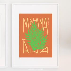Puede incluir: Impresión artística enmarcada con las palabras "MELAMA AINA" en fuente naranja claro, con un diseño de helecho verde sobre un fondo naranja. La obra de arte se muestra en un marco blanco.