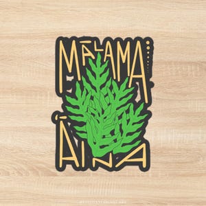 Puede incluir: Una pegatina con las palabras "MALAMA AINA" en amarillo, delineadas en negro. La palabra "MALAMA" está encima de un diseño de helecho verde, y "AINA" debajo. La pegatina tiene un borde negro.