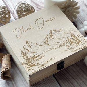 May include: A wooden box with a hinged lid and a metal latch. The box is engraved with a mountain scene and the text "Oliver Queen".