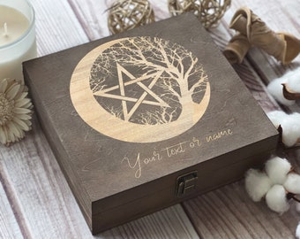 May include: A dark brown wooden box with a hinged lid and a brass latch. The box is engraved with a pentacle, a tree, and a crescent moon. The text "Your text or name" is engraved below the design.