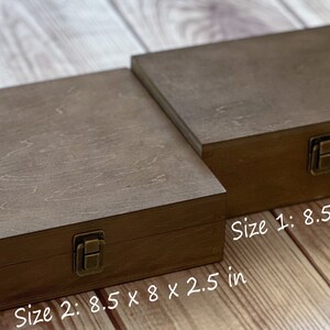 May include: Two wooden boxes with hinged lids and brass clasps. The larger box measures 8.5 inches by 8 inches by 2.5 inches. The smaller box measures 8.5 inches by 6 inches by 3 inches.