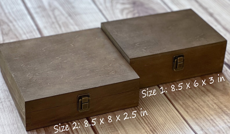 May include: Two wooden boxes with hinged lids and brass clasps. The larger box measures 8.5 inches by 8 inches by 2.5 inches. The smaller box measures 8.5 inches by 6 inches by 3 inches.