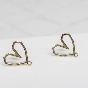 May include: A pair of gold-toned heart-shaped earrings with a geometric design. The earrings have a small loop at the bottom for attaching to a hook.
