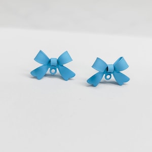 May include: Two light blue bow-shaped metal buttons with a hole in the center.