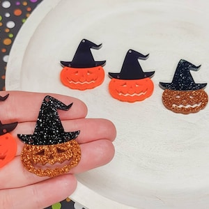 May include: Five Halloween-themed pumpkin ornaments with black witch hats. Two pumpkins are orange with black glitter hats, and three pumpkins are orange with black solid hats.
