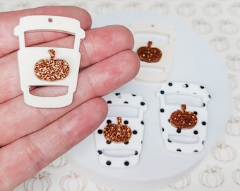 May include: White coffee cup shaped acrylic blanks with a glitter pumpkin design. The blanks are perfect for crafting and creating custom earrings, keychains, or other accessories.