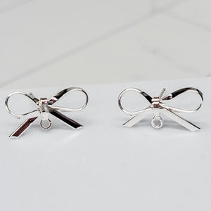 Puede incluir: Dos abalorios de plata en forma de lazo para pendientes con un bucle para sujetarlos a las joyas.