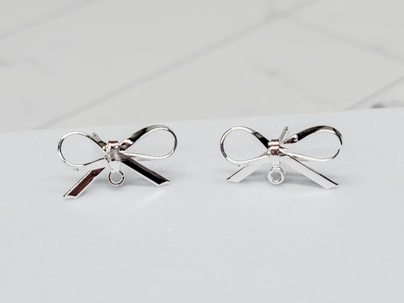 Puede incluir: Dos abalorios de plata en forma de lazo para pendientes con un bucle para sujetarlos a las joyas.