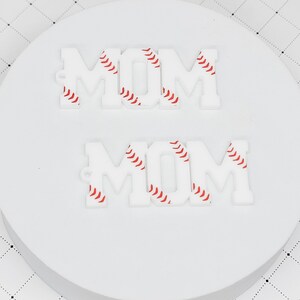 May include: Two white acrylic "MOM" signs with a baseball pattern. The letters are outlined in red.
