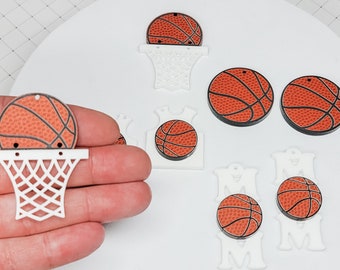 May include: A set of white and orange basketball themed craft supplies. The set includes basketballs with a textured surface, basketball hoops, and the word "MOM" in white.