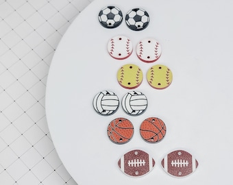 May include: A set of 10 wooden sports-themed buttons with different sports ball designs, including soccer, baseball, softball, volleyball, basketball, and football. The buttons are painted in various colors, including white, black, red, yellow, orange, and brown.