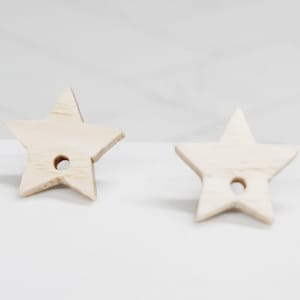 May include: Two unfinished wooden star shapes with a hole in the center. The stars are light brown and have a smooth surface.