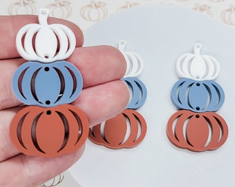 Op de afbeelding: Drie gestapelde pompoen-vormige bedels in wit, blauw en oranje. De bedels zijn gemaakt van acryl en hebben een gat aan de bovenkant om op te hangen.