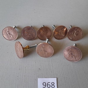 May include: Eight copper-colored coin-shaped drawer pulls with a screw on the back. The coins feature a profile of a woman and the year 1937.