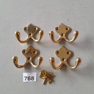 May include: Four gold double hooks with a decorative design and a pack of screws. The number 768 is written on a white piece of paper.