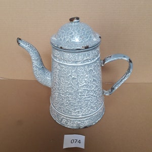 May include: A vintage, light blue and white enamelware coffee pot with a textured surface. The pot has a lid, a spout, and a handle. The number "074" is on a small white label.