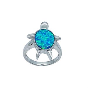 Può includere: Un anello d'argento con un design a forma di tartaruga marina. Il guscio della tartaruga è un opale blu-verde vibrante e rotondo. La fascia dell'anello e il corpo della tartaruga sono in argento lucido. Le pinne e la testa della tartaruga sono ben definite.