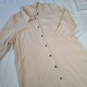 May include: A long-sleeved, light pink button-down shirt with a collared neckline. The shirt has a relaxed fit and is made of a lightweight fabric.