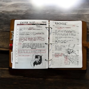 May include: A leather-bound planner open to two pages with handwritten notes and illustrations. One page is titled "Goober Dust" with a schedule and action list. The other page is titled "Rakshasa" with notes. The planner is on a wooden surface.