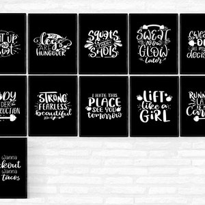 May include: A collection of black framed wall art with white text. The art features motivational phrases related to fitness, such as "Shut up and squat", "My legs are hungover", and "Lift like a girl". The overall theme is fitness and workout.