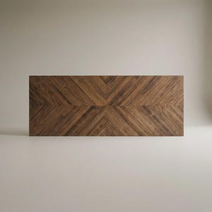 May include: A rectangular wooden tabletop featuring a dark brown walnut grain with a symmetrical chevron pattern. The wood planks are arranged in diagonal lines that meet at a central seam, creating a distinct V-shaped design across the surface.