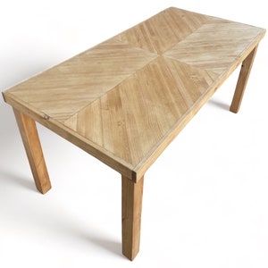 May include: A rectangular wooden table with a light brown finish. The tabletop features a geometric pattern, and the legs are angled. The table is approximately 60 inches long and 30 inches wide.