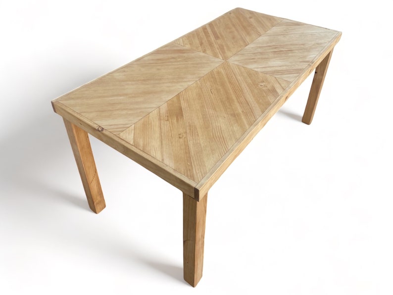 May include: A rectangular wooden table with a light brown finish. The tabletop features a geometric pattern, and the legs are angled. The table is approximately 60 inches long and 30 inches wide.