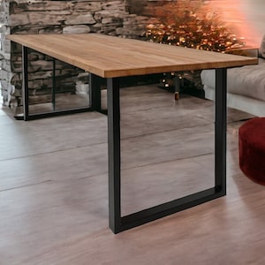 Può includere: Un tavolo rettangolare in legno con superficie marrone chiaro e gambe in metallo nero. Il tavolo misura circa 183 cm di lunghezza e 91 cm di larghezza. Le gambe hanno un design semplice e moderno, in una stanza con un muro di pietra.