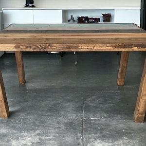 Peut inclure: Une table en bois rustique avec un plateau multicolore et quatre pieds. Le plateau de la table est en bois de récupération avec une finition naturelle. Les pieds sont de couleur brun foncé et sont en bois massif.