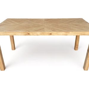 May include: A rectangular wooden dining table with a light brown finish. The tabletop features a chevron pattern, and the legs are angled for stability. The table is approximately 72 inches long and 36 inches wide.