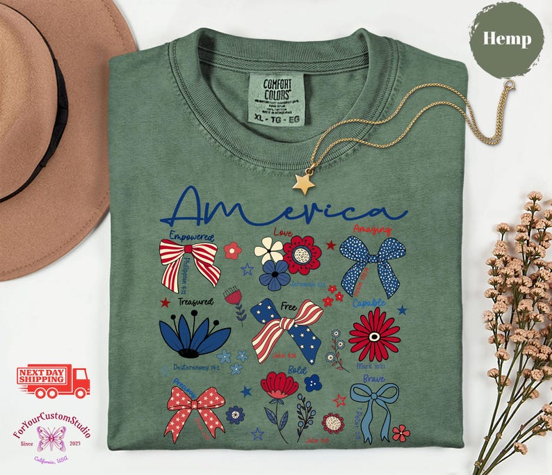 May include: Green t-shirt with the word "America" in blue script, decorated with patriotic bow and flower graphics in red, white, and blue. A gold star pendant necklace rests on the shirt.