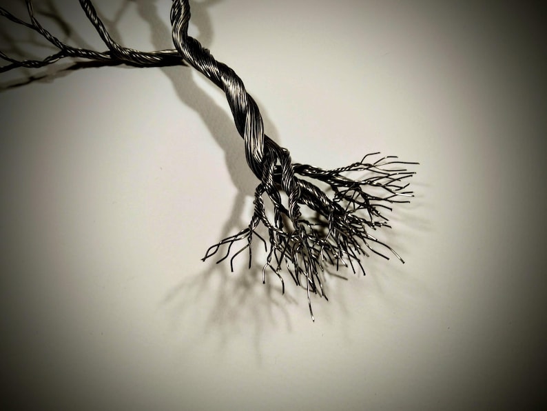 May include: A metal sculpture of a tree with a twisted trunk and many branches. The sculpture is made of thin wire and has a dark, metallic finish.