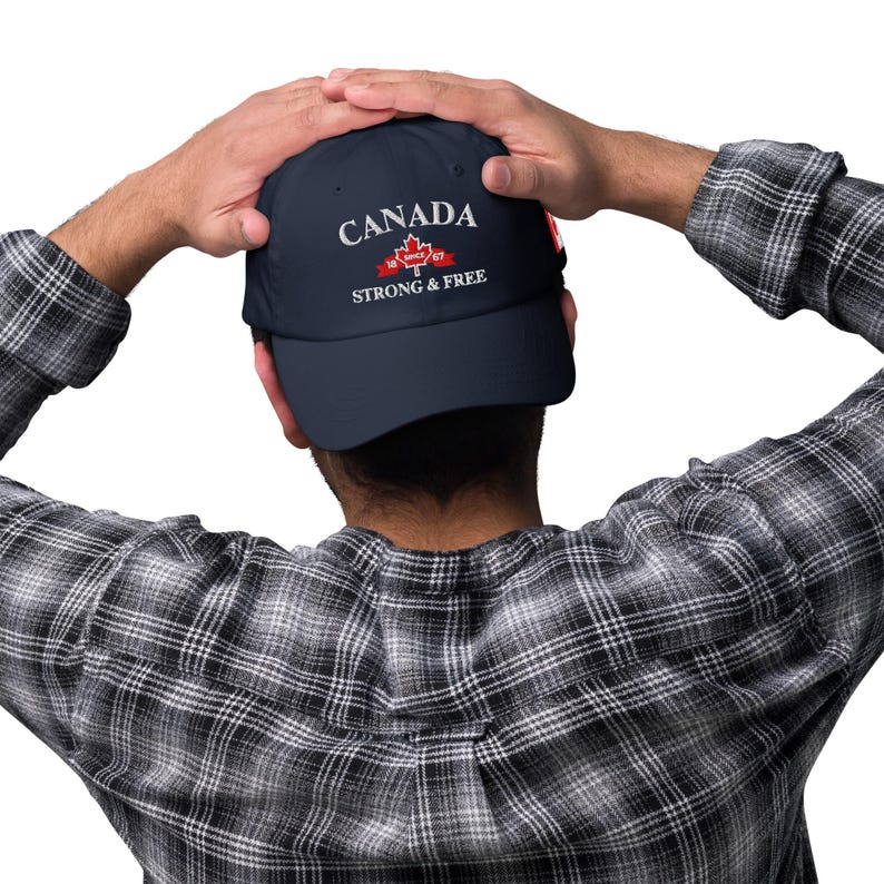 May include: A navy blue baseball cap with white embroidery that reads "CANADA 1867 STRONG & FREE". The cap features a red maple leaf with a white outline.