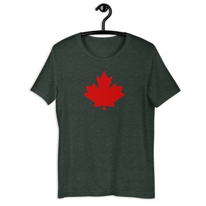 Puede incluir: Una camiseta de manga corta en color gris carb&oacute;n jaspeado oscuro con un gr&aacute;fico de una hoja de arce roja s&oacute;lida y vibrante centrado en el pecho. La prenda tiene un cuello redondo cl&aacute;sico y se muestra en una percha de pl&aacute;stico negra.