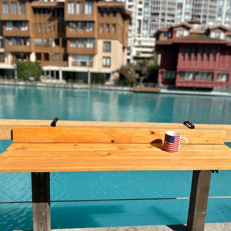 May include: A wooden table with a mug featuring the American flag. The table is made of light brown wood and has a simple design. The mug is white with red and blue stripes and stars.