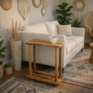 May include: A rectangular wooden side table with a smooth top surface and a lower shelf, supported by four cylindrical legs. The table is constructed from light brown wood with a visible grain pattern and features a simple, functional design.