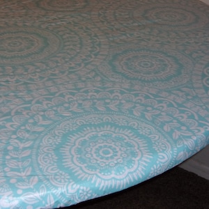 Fitted tablecloth. PEVA/ felt backing White with turquoise medallion 70&quot; will fit 60&quot; or 48x65 oval table. The 60x84  will fit a 48x72