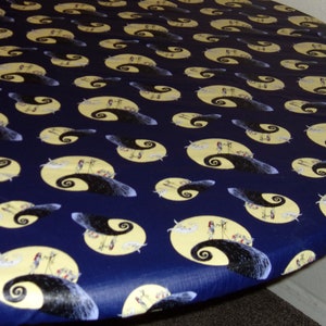 Peut inclure: Une nappe ronde bleue avec un motif r&eacute;p&eacute;t&eacute; d'une lune jaune et une silhouette noire d'une colline avec un chemin sinueux. La colline est tir&eacute;e du film L'&Eacute;trange No&euml;l de monsieur Jack.