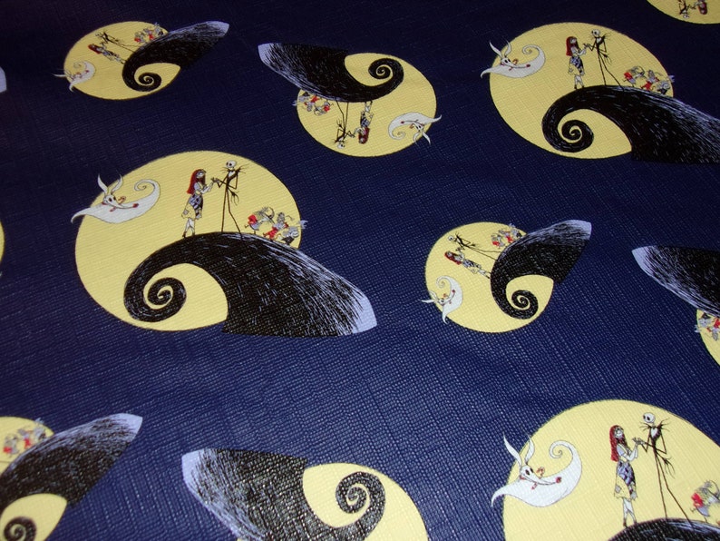 Peut inclure: Un tissu bleu avec un motif r&eacute;p&eacute;t&eacute; de Jack Skellington et Sally du film L'&Eacute;trange No&euml;l de monsieur Jack. Les personnages sont debout sur un croissant de lune jaune avec un tourbillon noir.
