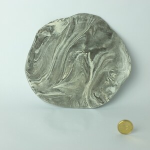 May include: A grey and white marbled ceramic dish with an irregular shape. The dish is approximately 25 cm in diameter.