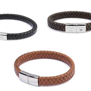 Könnte beinhalten: Drei geflochtene Lederarmbänder mit silbernen Verschlüssen. Jedes Armband hat eine andere Inschrift auf dem Verschluss: "EST 2016", "Ich liebe dich" und "DADDY".