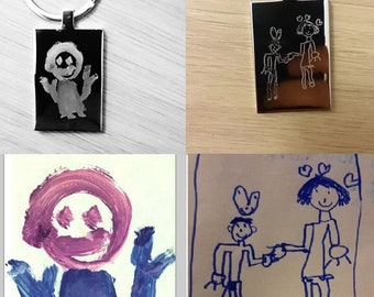 May include: Two silver keychains with engraved drawings of children. The drawings are simple and childlike, with one showing a single figure and the other showing two figures holding hands.