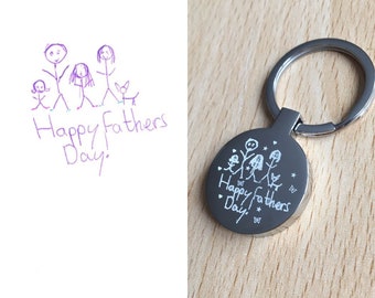 May include: A silver keychain with a round charm engraved with a stick figure family drawing and the text "Happy Fathers Day".