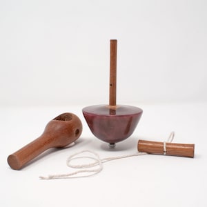 May include: A traditional wooden spinning top toy, featuring a dark red body and a brown wooden handle. The set includes a wooden handle, a string, and a wooden winder. The toy is designed for play and entertainment.