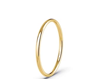 Puede incluir: Un anillo de banda de oro amarillo pulido y fino con un perfil liso y redondeado. La superficie interior de la banda de metal presenta el texto grabado 750 AFJ, que indica la pureza del oro y la marca del fabricante en esta joya circular.