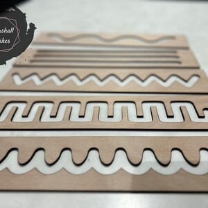 May include: Set of five wooden stencils with different patterns, including wavy lines, zigzags, and a more complex design. The stencils are made of light brown wood and have a natural finish.