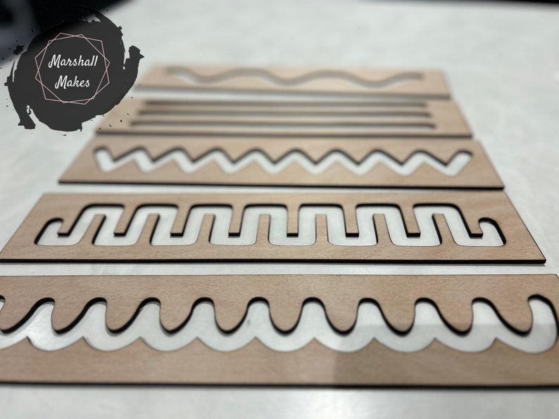 May include: Set of five wooden stencils with different patterns, including wavy lines, zigzags, and a more complex design. The stencils are made of light brown wood and have a natural finish.