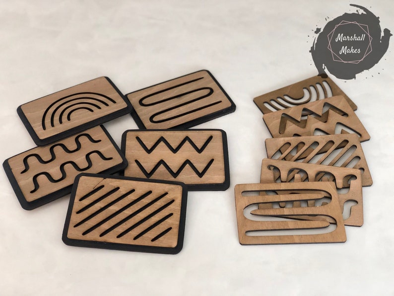 May include: Set of eight wooden tiles with black outlines, each featuring a different geometric design. The designs include a rainbow, wavy lines, zigzags, and stripes.
