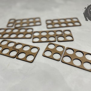 May include: Eight wooden paint palettes with circular cutouts for holding paint pots. The palettes are arranged in a scattered pattern on a white surface.